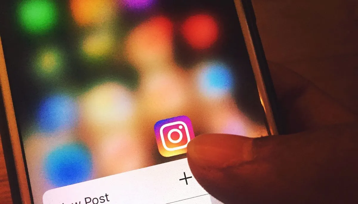 Palec dotykający ikony aplikacji Instagram na ekranie smartfona