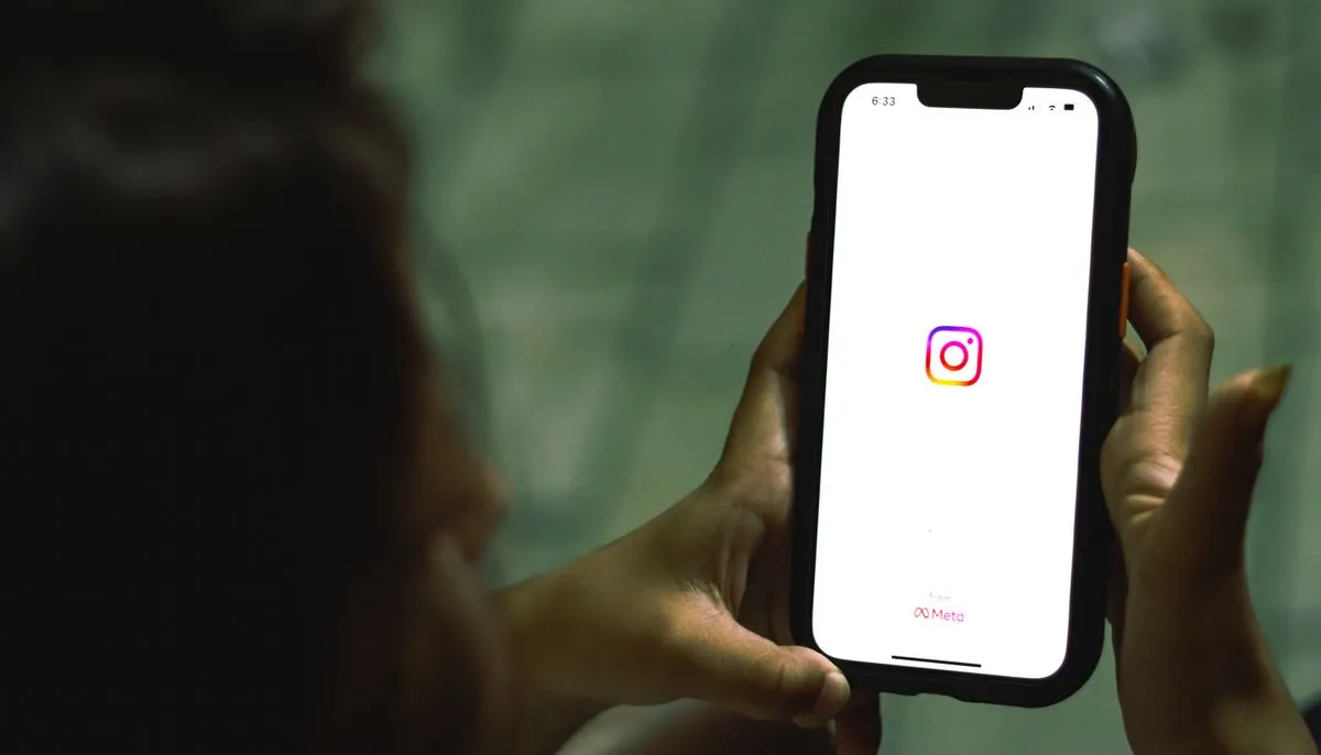 Dłonie trzymające telefon z otwartą aplikacją Instagram — konto profesjonalne na Instagramie
