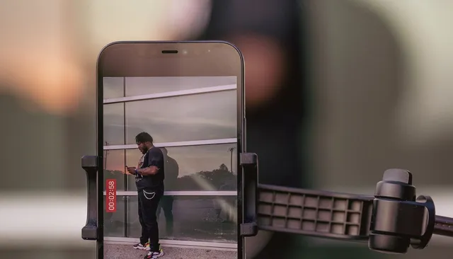 Osoba nagrywająca pionowe wideo smartfonem na statywie — jak robić Reels na Instagramie