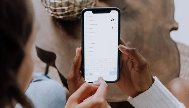 Dłonie trzymające smartfon z otwartym ekranem wyszukiwania — Instagram SEO i optymalizacja profilu