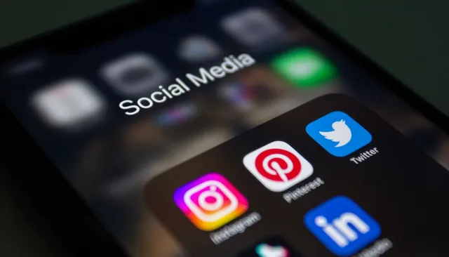 Ekran smartfona z folderem aplikacji social media (Instagram, Pinterest) — ilustracja zwiększania zasięgów na Instagramie