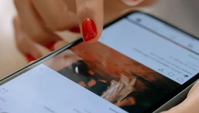 Kobieta trzymająca smartfon z otwartym Instagramem — jak zdobyć obserwujących na Instagramie